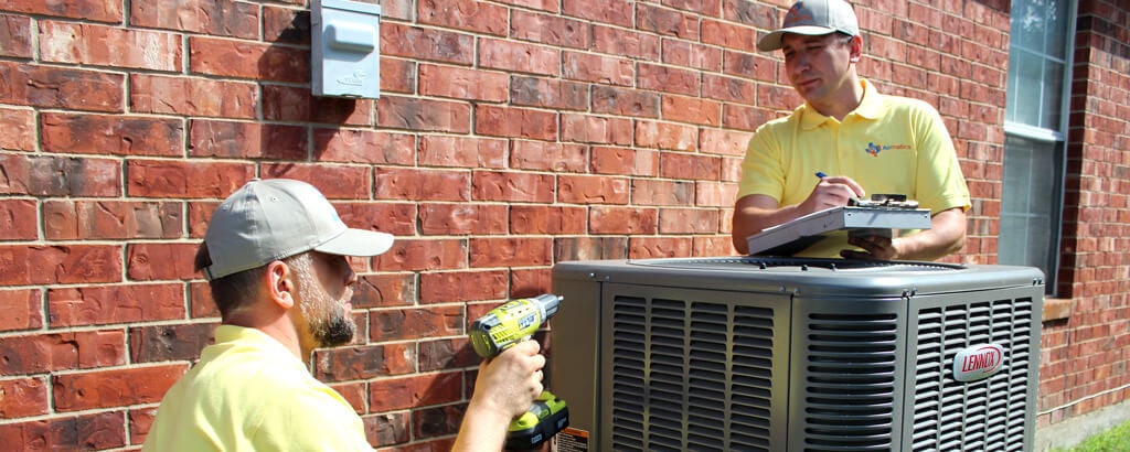 A professional HVAC technician working on an outdoor condenser unit